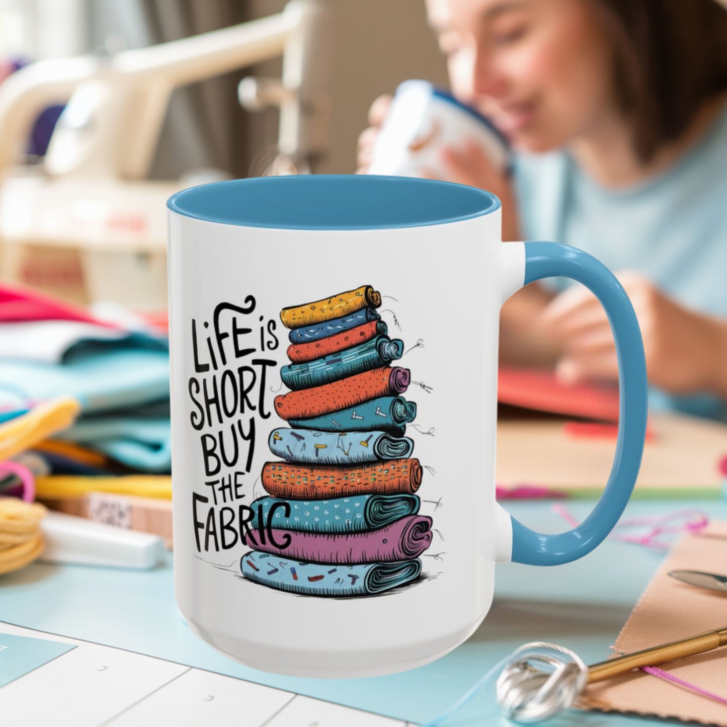 A funny Ceramic Mug with the phrase Life is Short, Buy the Fabric with the label 'Life is Short, Buy the Fabric' next to a graphic of A funny pile of fabric
