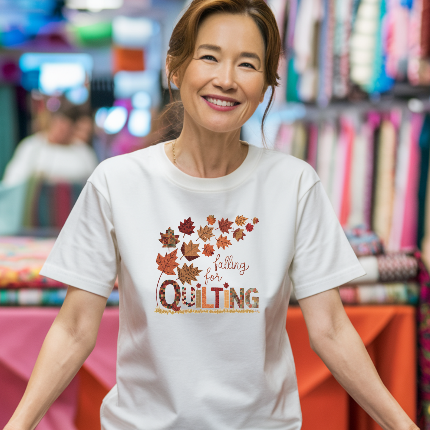 A thanksgiving quilting t-shirt featuring autumn leaves with various quilting patterns inside. Text reads "falling for QUILTING" with letters in patchwork style. Warm fall colors and quilting motifs combine in a seasonal design.