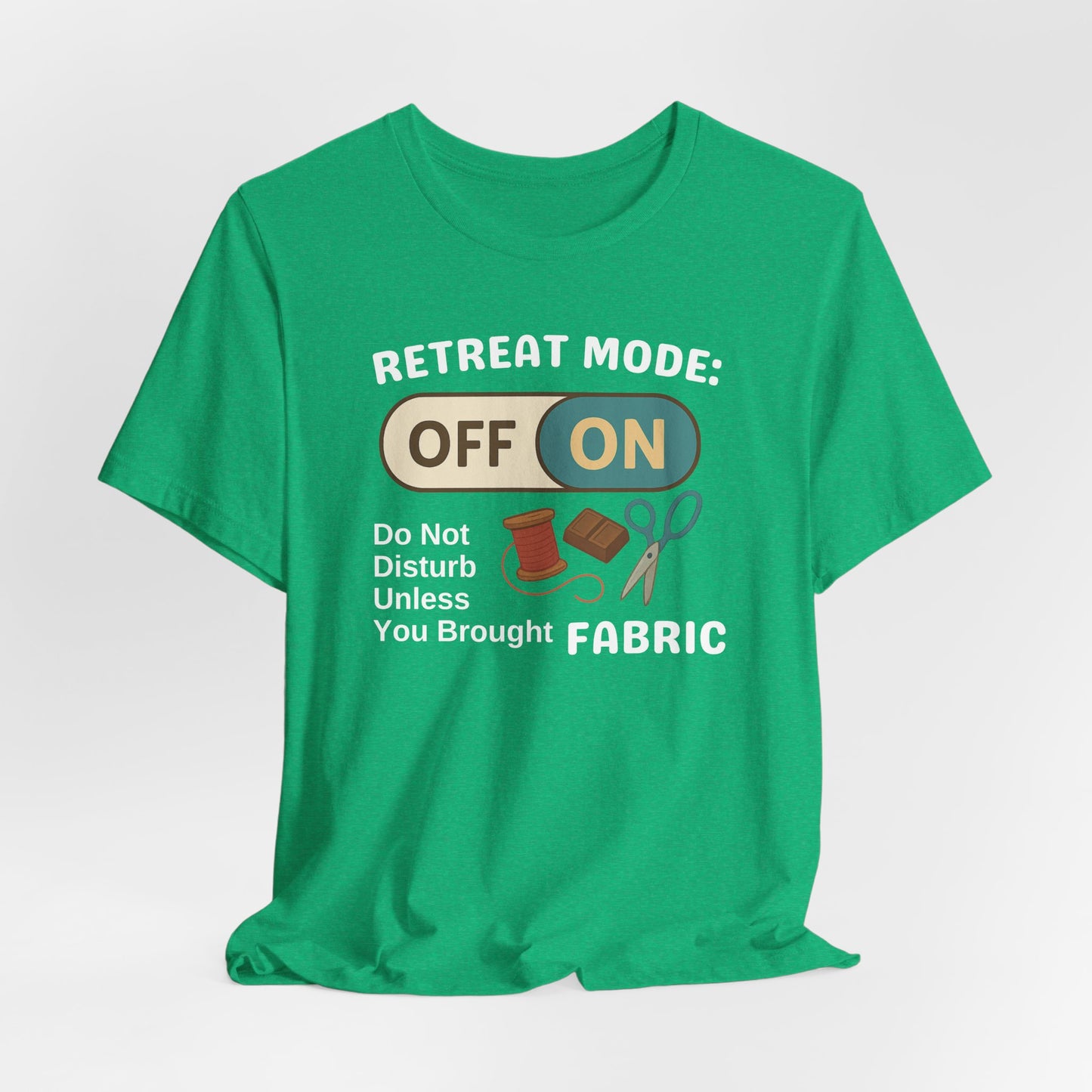 A A Heather Kelly t-shirt with a toggle switch that says "Retreat Mode: OFF/ON" surrounded by a spool of thread, chocolate, and scissors. Text below reads "Do not disturb unless you brought fabric." Fun gift for quilting retreats.