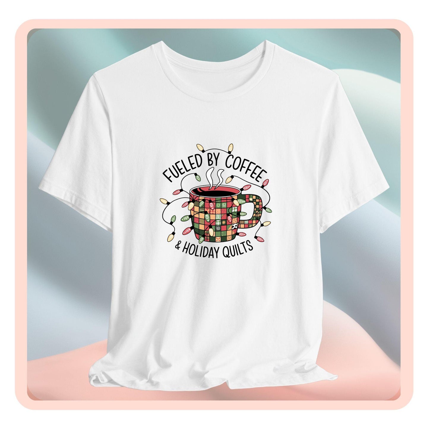 A christmas quilting t-shirt featuring a cozy coffee mug covered in patchwork quilt patterns, wrapped in festive holiday lights, with the phrase "Fueled by Coffee & Holiday Quilts" surrounding the design.