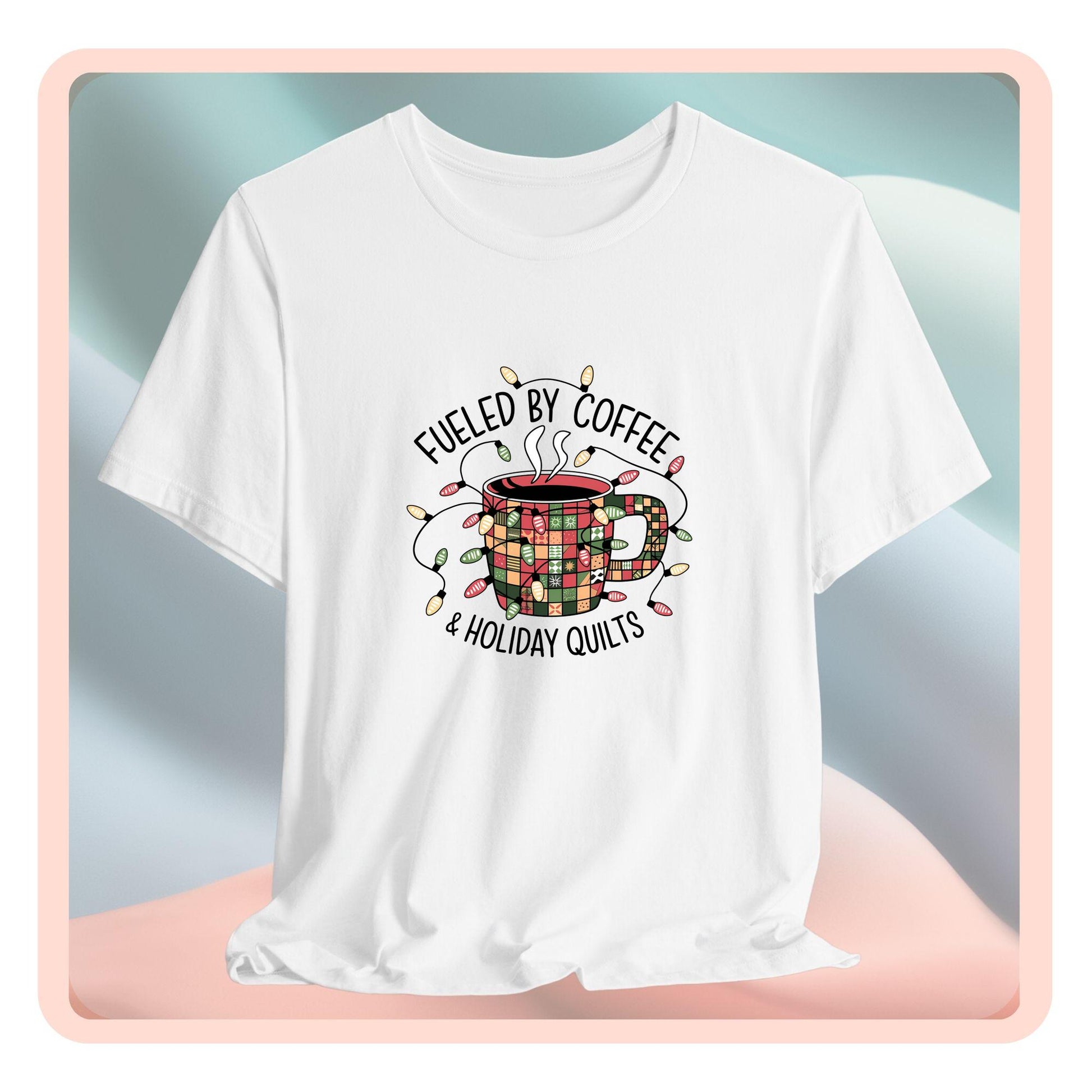A christmas quilting t-shirt featuring a cozy coffee mug covered in patchwork quilt patterns, wrapped in festive holiday lights, with the phrase "Fueled by Coffee & Holiday Quilts" surrounding the design.