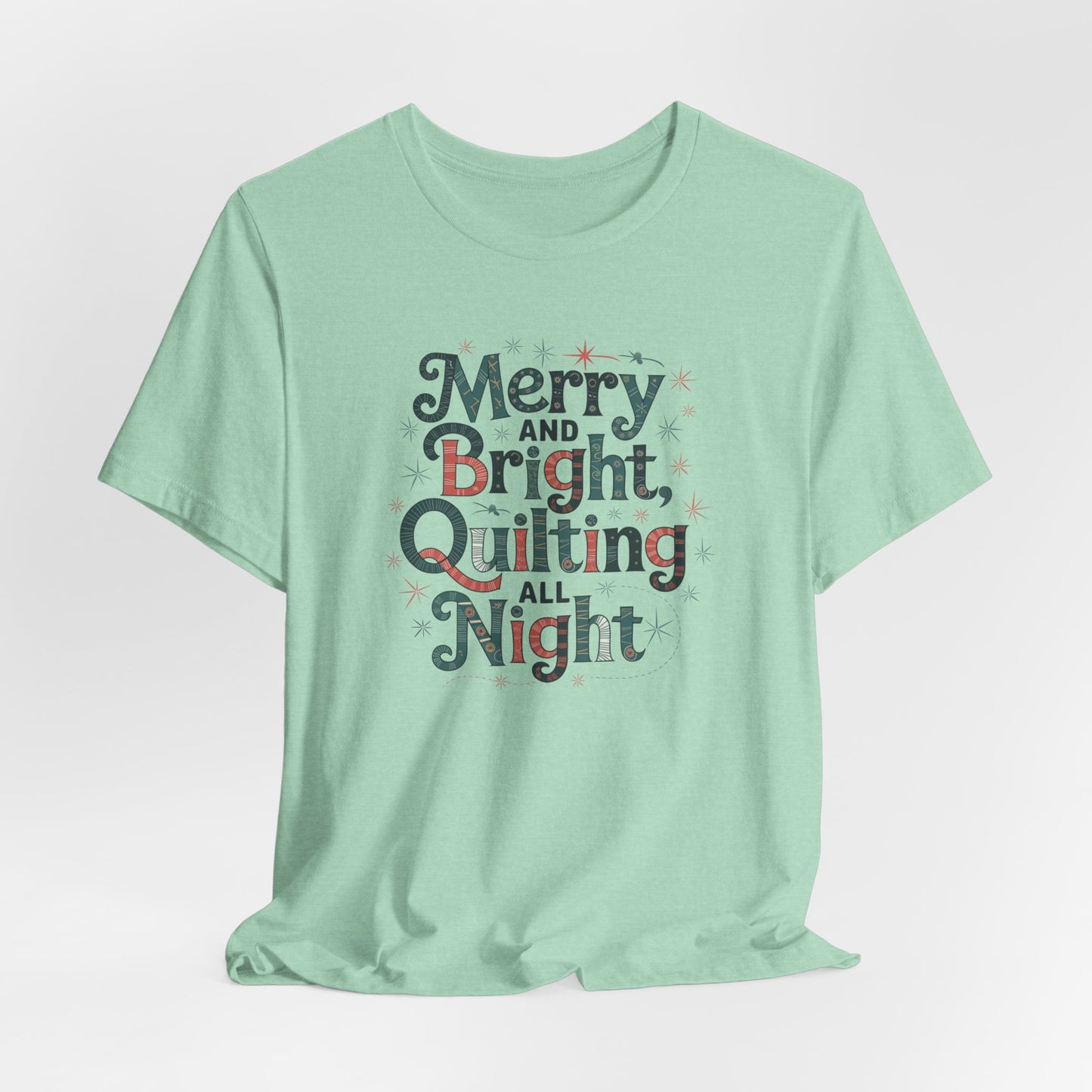 A Heather Mint christmas quilting T-shirt featuring a whimsical design with the phrase "Merry and Bright, Quilting All Night," featuring festive quilting patterns and holiday-themed elements like stars and stitching lines. Perfect gift for quilters.