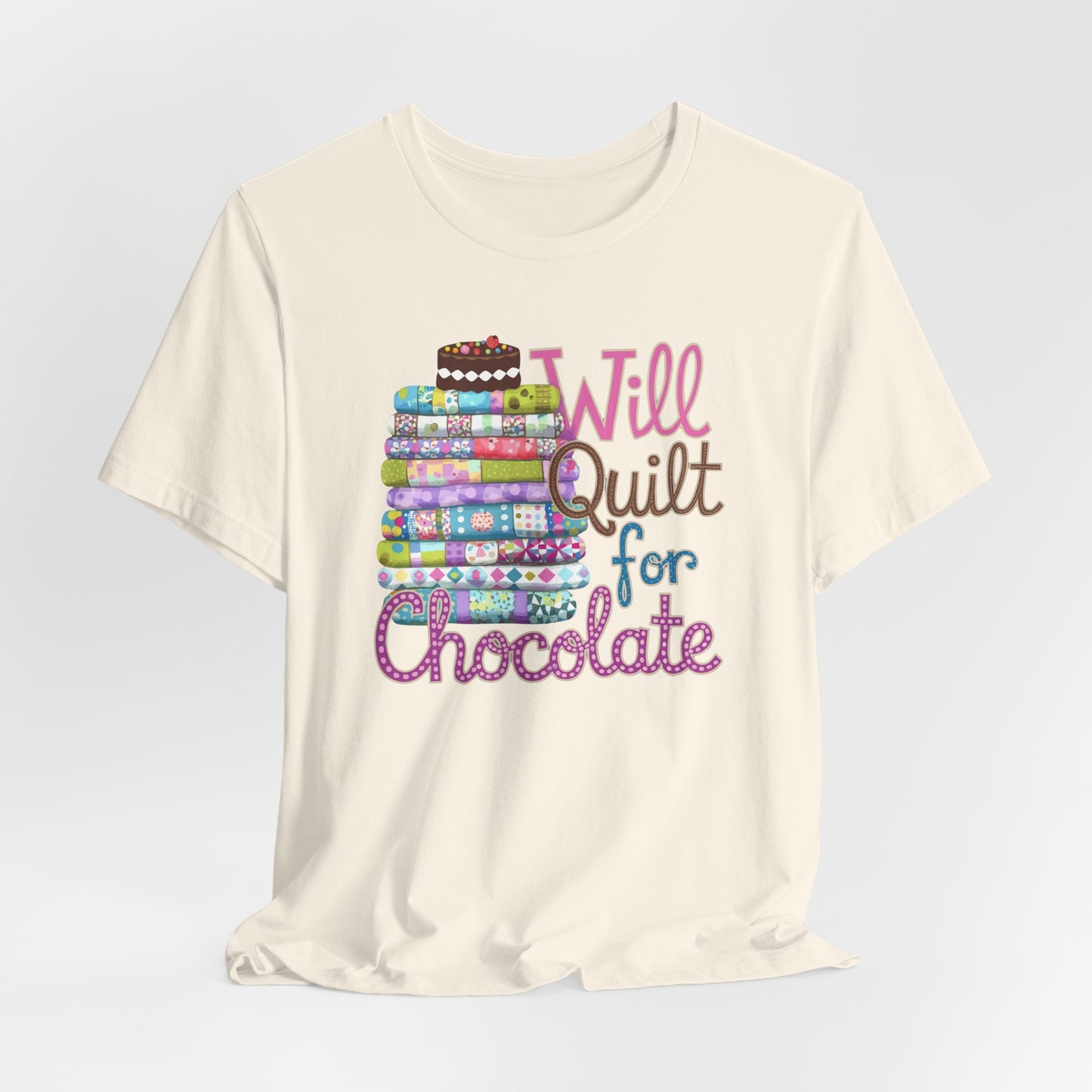A Natural t-shirt featuring a whimsical design of a colorful stack of quilts topped with a chocolate cake and the phrase 'Will Quilt for Chocolate,' perfect for quilters who love sweets.