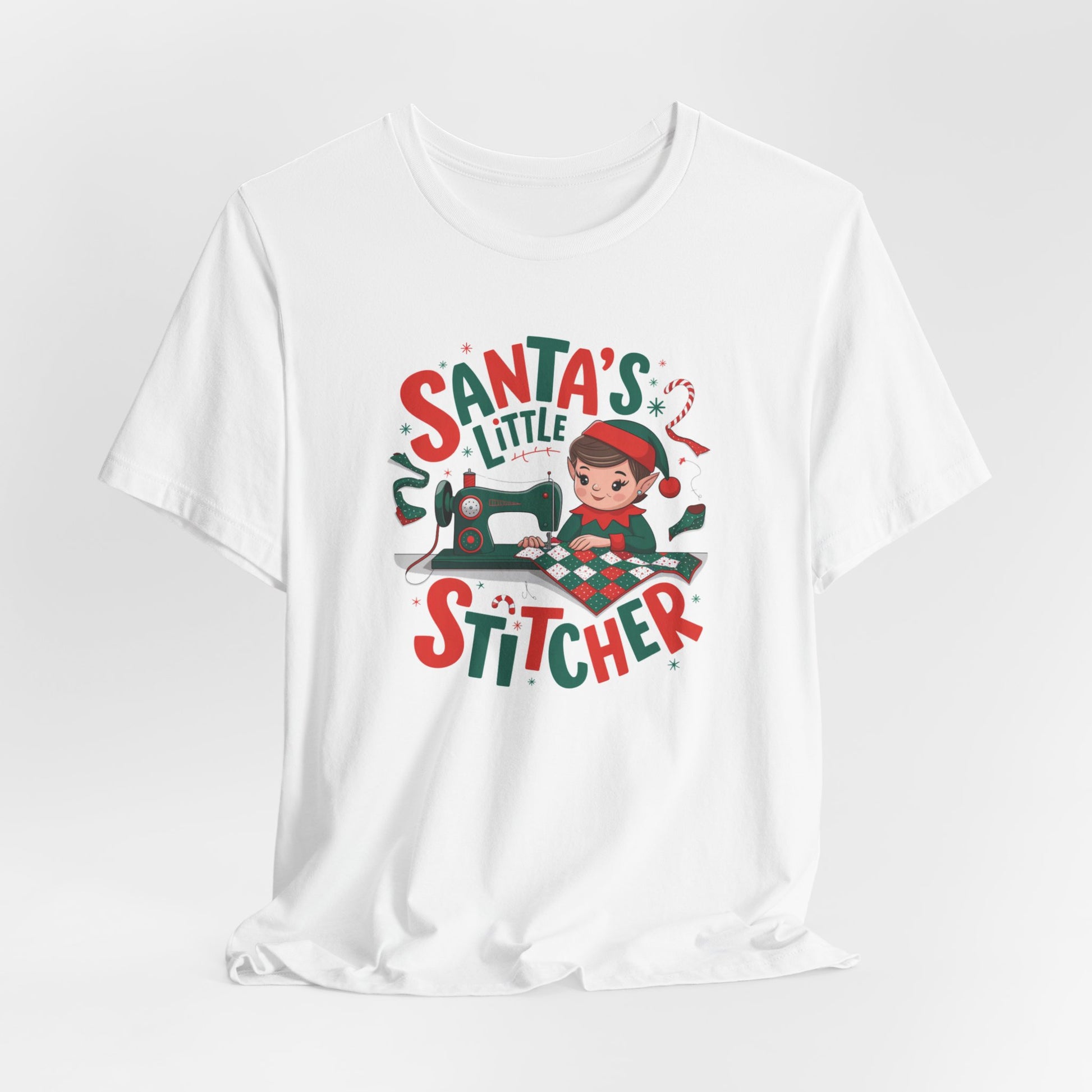 A White christmas quilting t-shirt featuring an adorable elf is sewing a festive patchwork quilt on a sewing machine, surrounded by holiday-themed decorations, with the phrase "Santa's Little Stitcher" above and below the design.