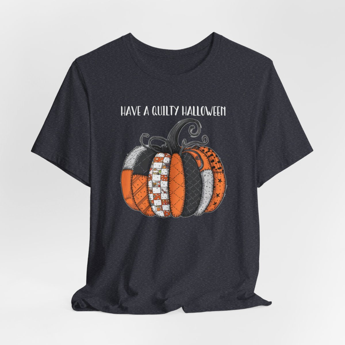 A Heather Navy Halloween Quilting T-Shirt featuring patchwork pumpkin with various quilt patterns. Mix of Halloween and traditional quilt motifs. Intricate stitching details. Text reads "Have a Quilty Halloween". Ideal for quilters who love Halloween.