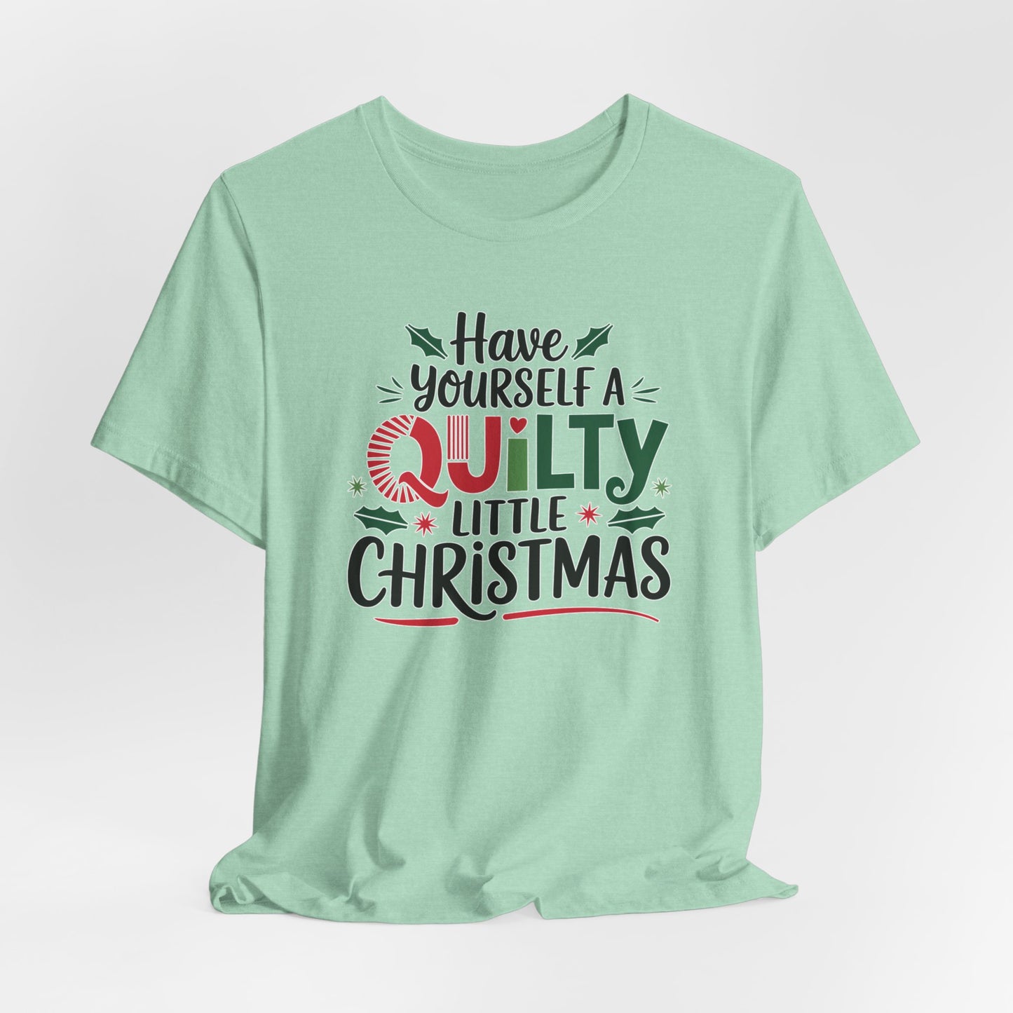 A Heather Mint fun holiday-themed t-shirt featuring the phrase "Have Yourself a Quilty Little Christmas" with quilting-inspired elements and holiday decorations such as holly and stars.