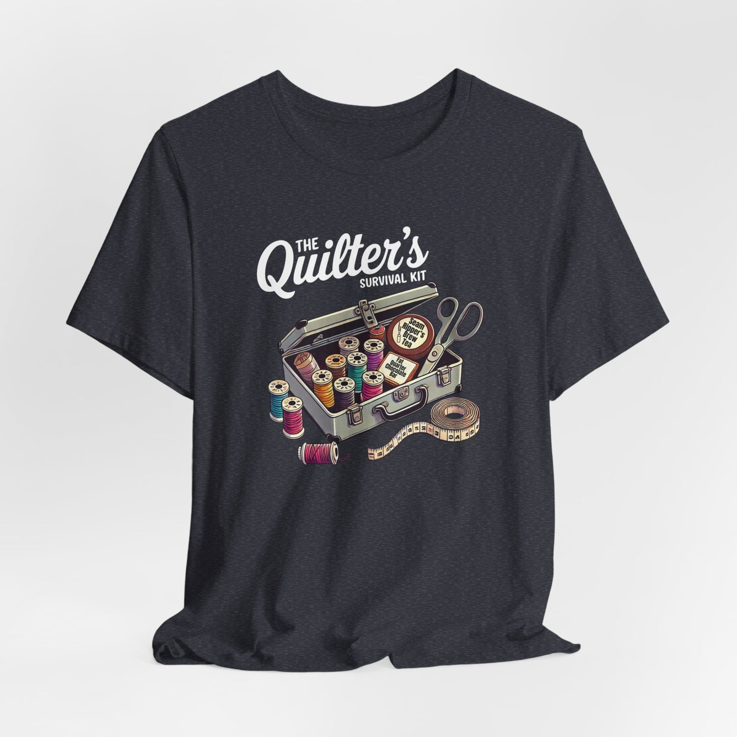 A Heather Navy t-shirt featuring a whimsical illustration of a quilter’s survival kit with colorful thread spools, scissors, and a tape measure, perfect for sewing and quilting enthusiasts.