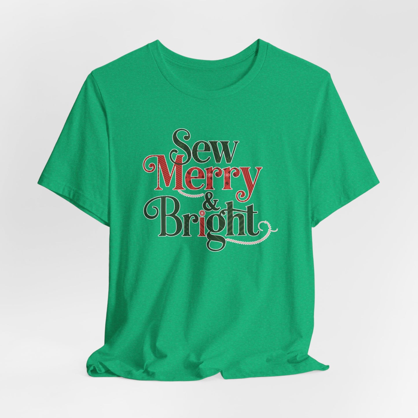 A Heather Kelly t-shirt with the phrase "Sew Merry & Bright," incorporating sewing-inspired elements and holiday-themed accents, such as stitching lines and festive patterns.