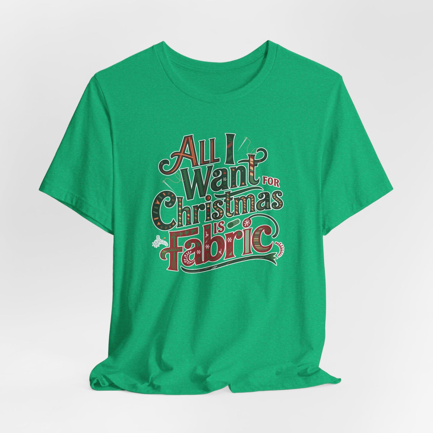 A Heather Kelly festive quilting christmas T-shirt featuring the phrase "All I Want for Christmas is Fabric," with fun sewing and quilting accents like needles and threads swirling around the text.