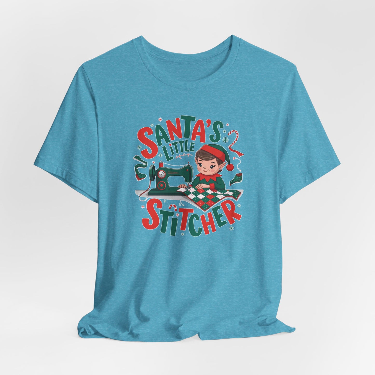 A Heather Aqua christmas quilting t-shirt featuring an adorable elf is sewing a festive patchwork quilt on a sewing machine, surrounded by holiday-themed decorations, with the phrase "Santa's Little Stitcher" above and below the design.