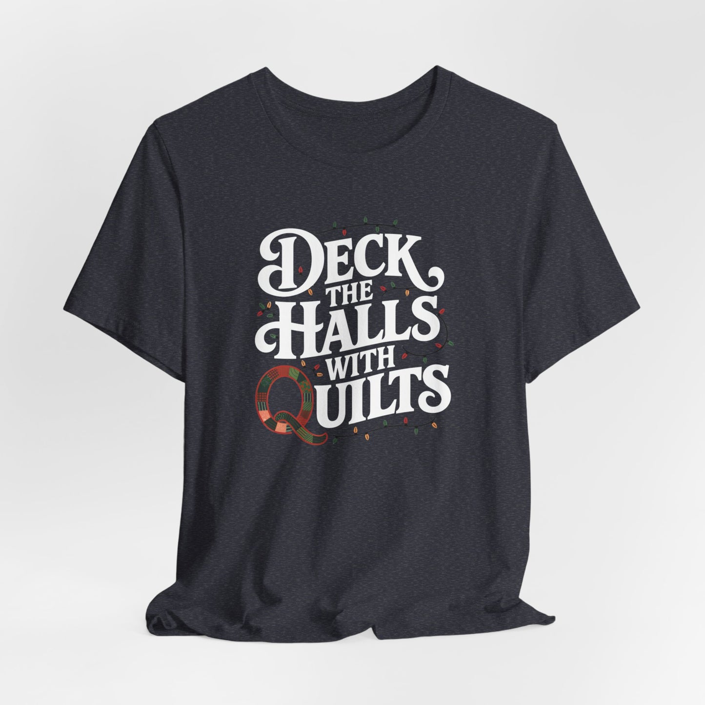 A Heather Navy christmas quilting t-shirt featuring the phrase "Deck the Halls with Quilts," adorned with holiday lights and quilting-inspired elements, including a quilted 'Q' for a humorous touch.