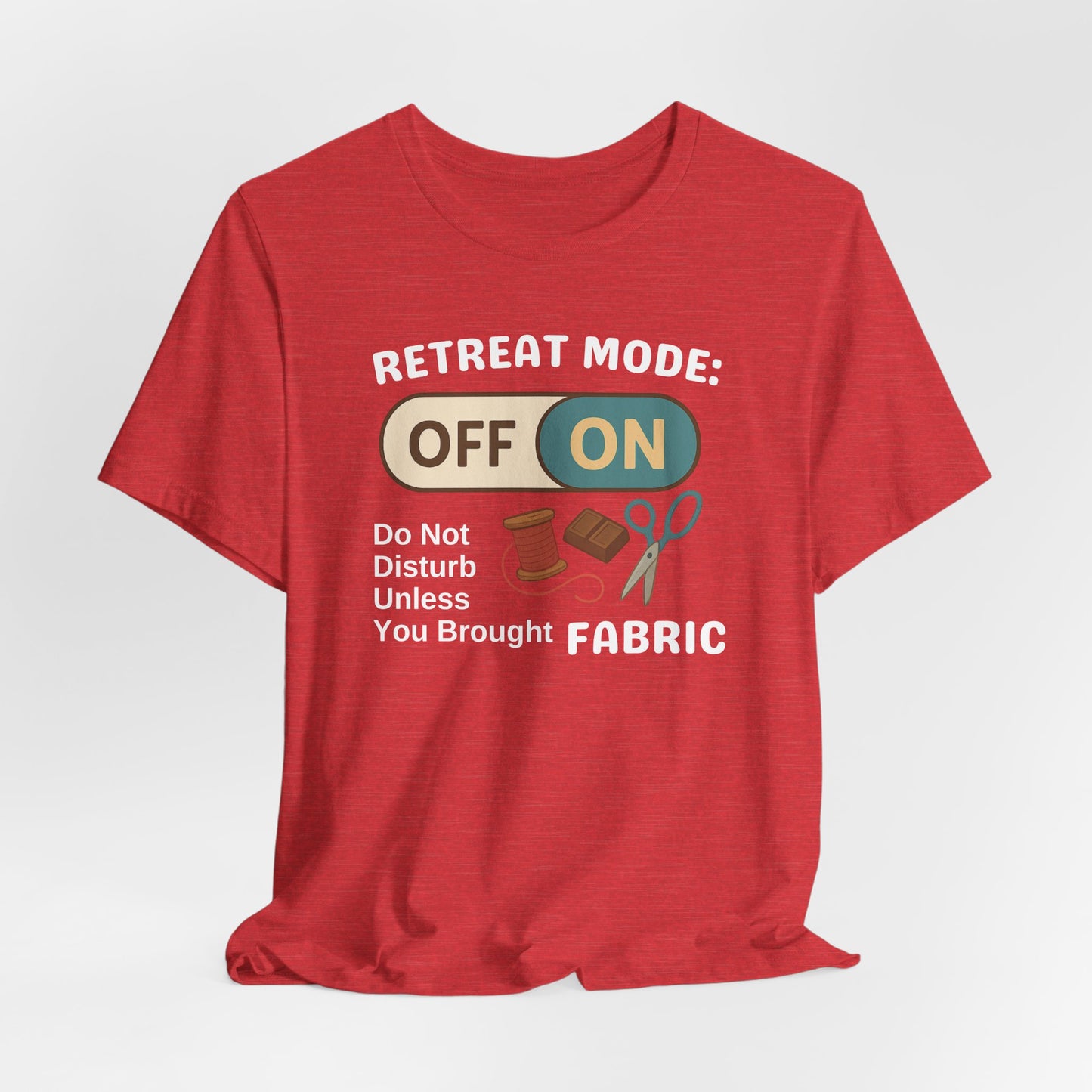 A A Heather Red t-shirt with a toggle switch that says "Retreat Mode: OFF/ON" surrounded by a spool of thread, chocolate, and scissors. Text below reads "Do not disturb unless you brought fabric." Fun gift for quilting retreats.