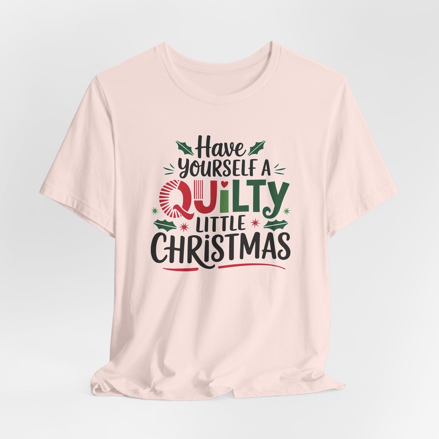 A Soft Pink fun holiday-themed t-shirt featuring the phrase "Have Yourself a Quilty Little Christmas" with quilting-inspired elements and holiday decorations such as holly and stars.