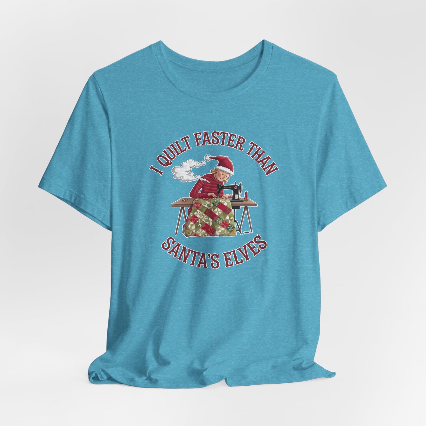 A Heather Aqua christmas quilting t-shirt featuring a quilter working at a sewing machine, quilting a festive holiday quilt, with the phrase "I Quilt Faster Than Santa's Elves" above the image, highlighting the speed and skill of the quilter.