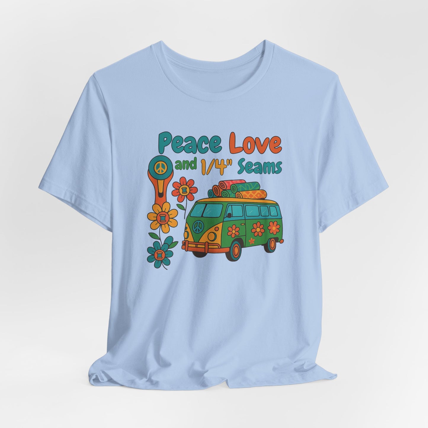 A A Baby Blue t-shirt with colorful retro design showing a peace sign rotary cutter, patchwork van, and text “Peace Love and 1/4" Seams.” Surrounded by flowers made of thread spools. Fun vintage-style quilting shirt.