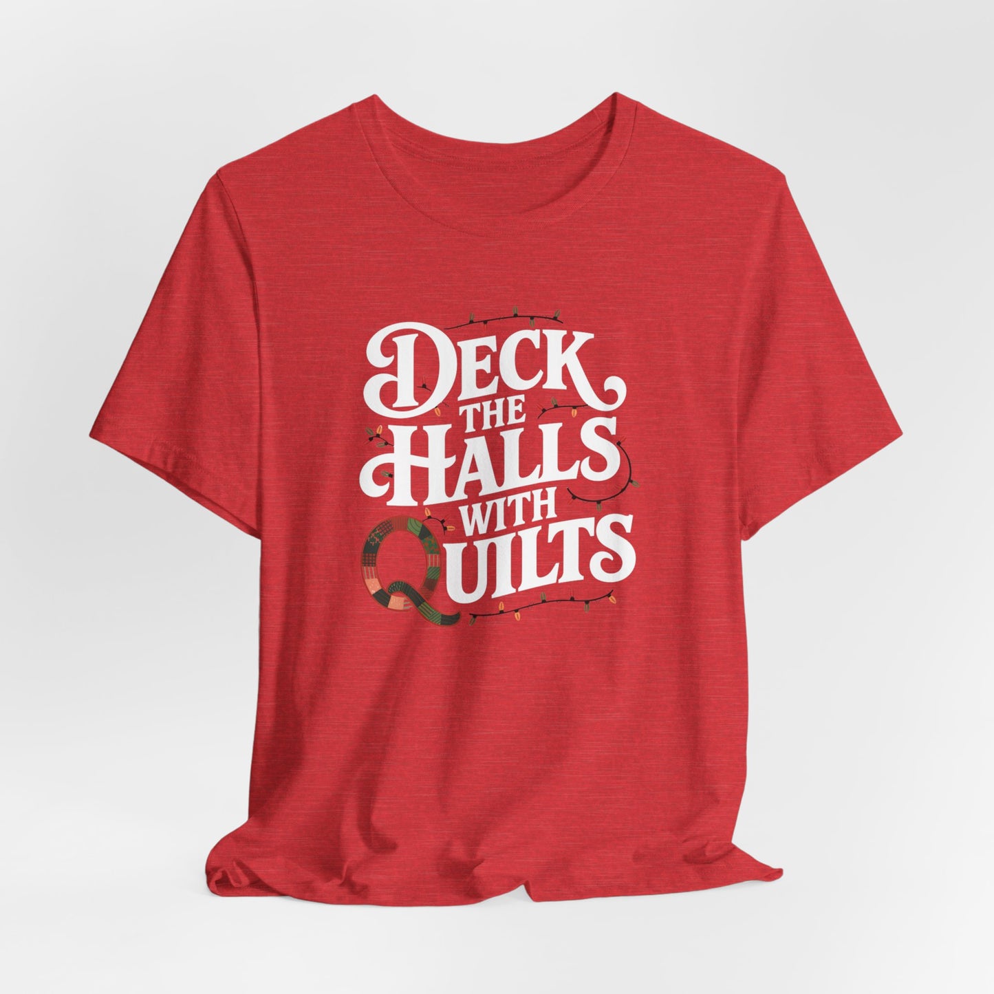 A Heather Red christmas quilting t-shirt featuring the phrase "Deck the Halls with Quilts," adorned with holiday lights and quilting-inspired elements, including a quilted 'Q' for a humorous touch.
