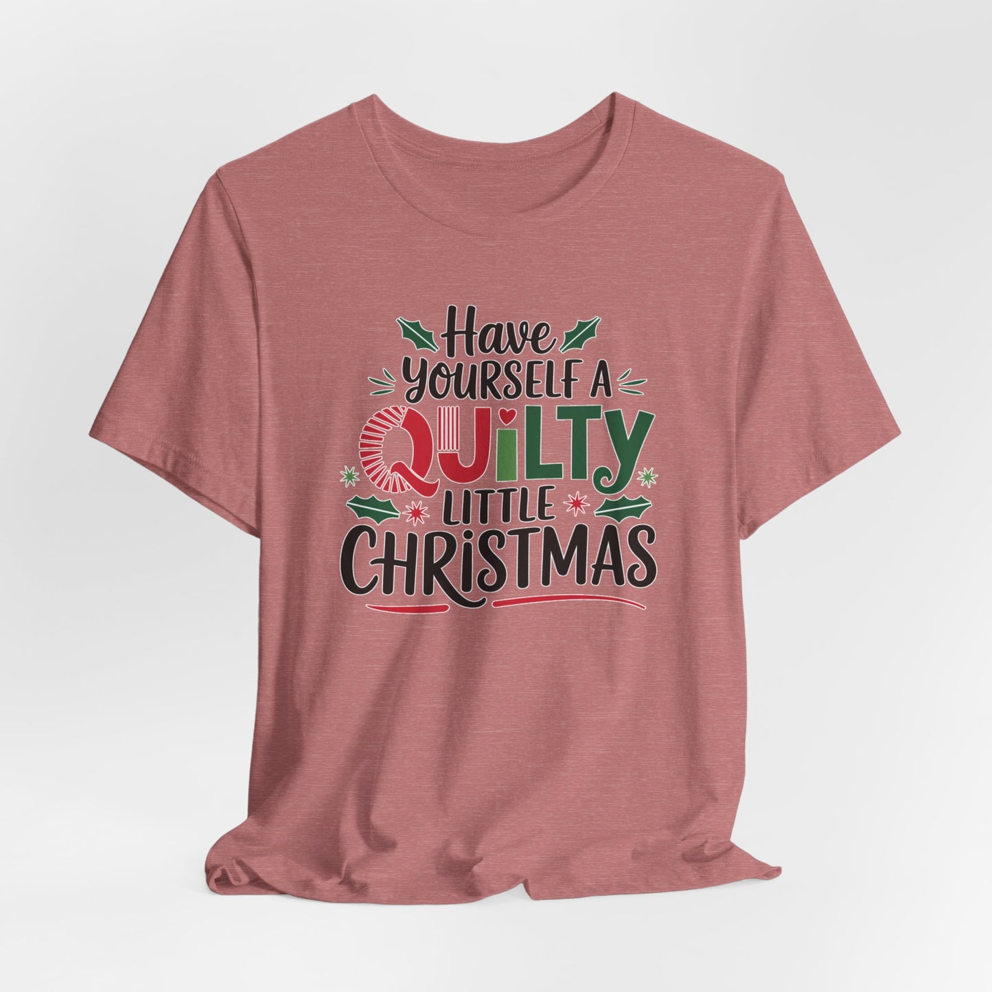 A Heather Mauve fun holiday-themed t-shirt featuring the phrase "Have Yourself a Quilty Little Christmas" with quilting-inspired elements and holiday decorations such as holly and stars.