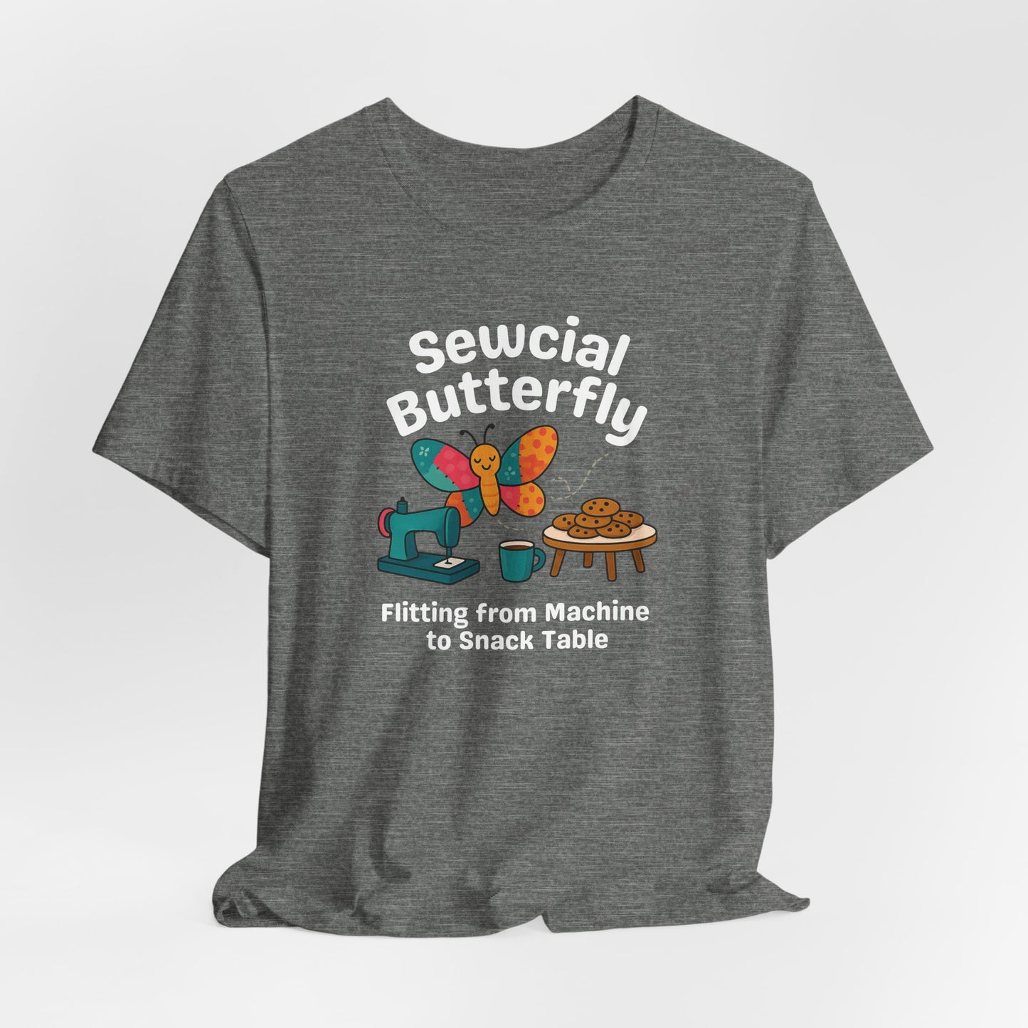 A A Deep Heather t-shirt with a colorful design showing a patchwork butterfly flying between a sewing machine and a table of cookies. Text reads “Sewcial Butterfly – Flitting from Machine to Snack Table.” Funny gift for quilters