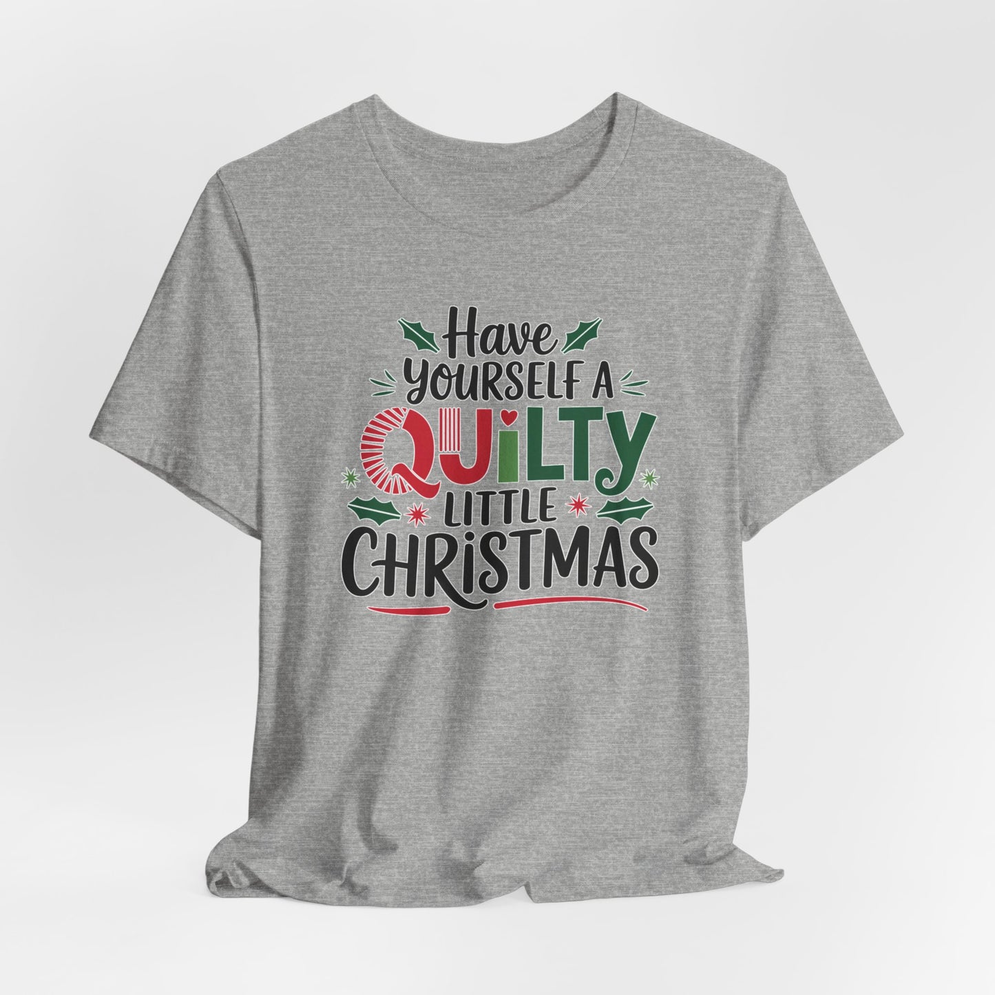 An Athletic Heather fun holiday-themed t-shirt featuring the phrase "Have Yourself a Quilty Little Christmas" with quilting-inspired elements and holiday decorations such as holly and stars.