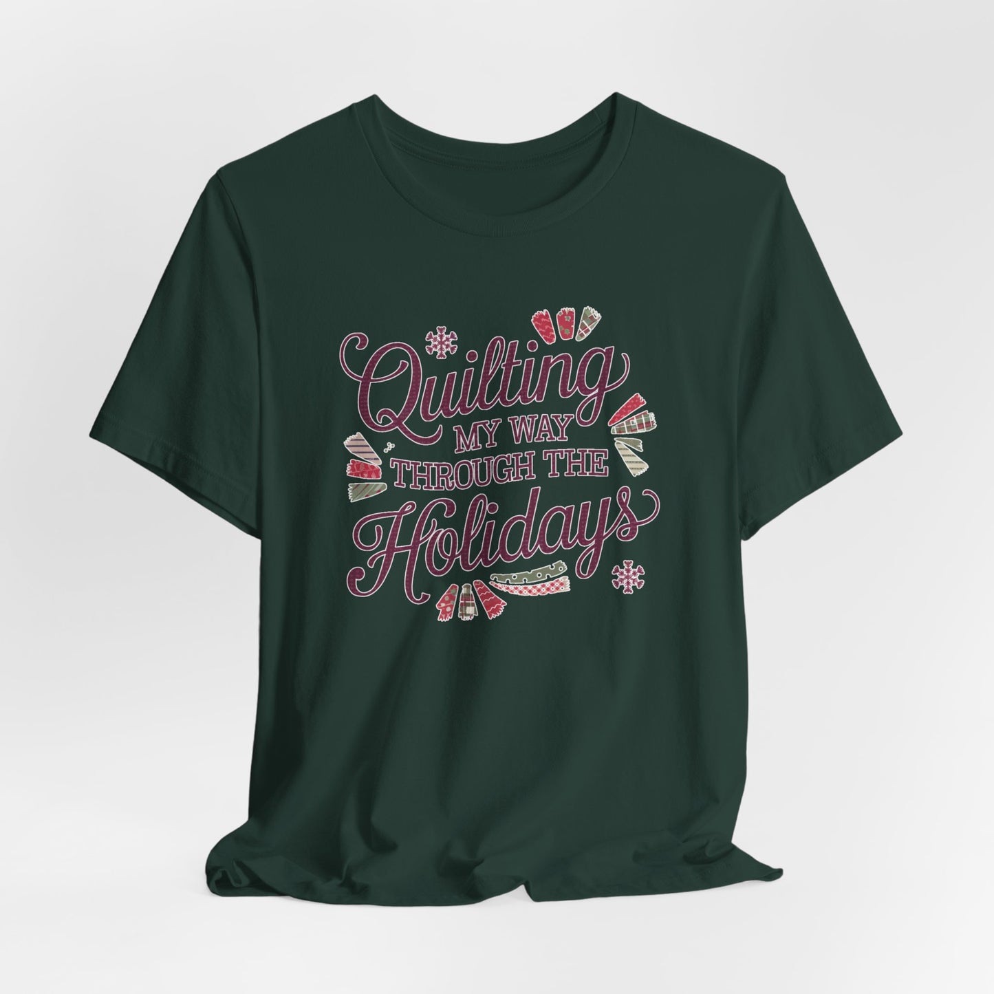 A Forest playful holiday-themed t-shirt with the phrase "Quilting My Way Through the Holidays" surrounded by quilting-inspired decorations like fabric swatches and snowflakes.