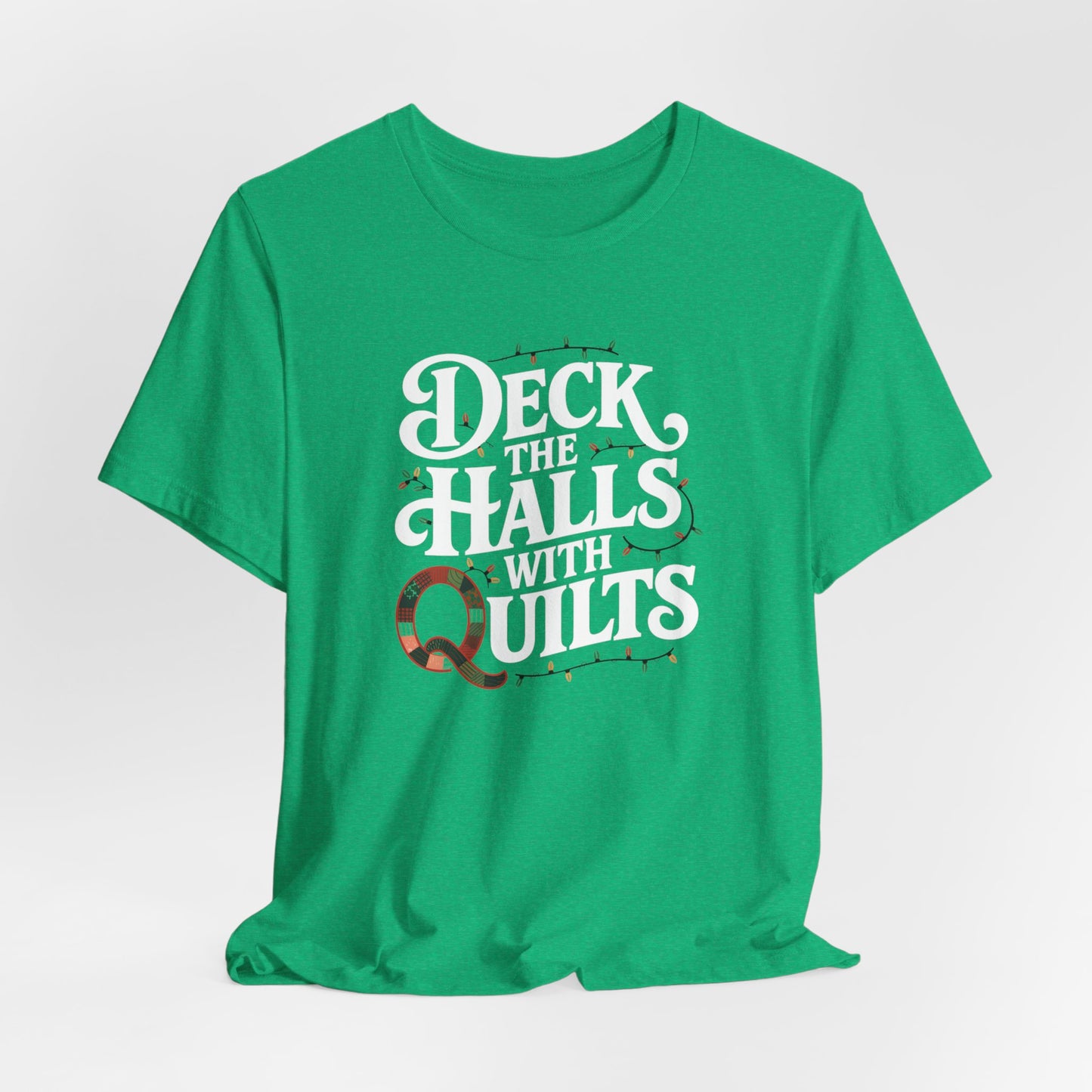 A Heather Kelly christmas quilting t-shirt featuring the phrase "Deck the Halls with Quilts," adorned with holiday lights and quilting-inspired elements, including a quilted 'Q' for a humorous touch.