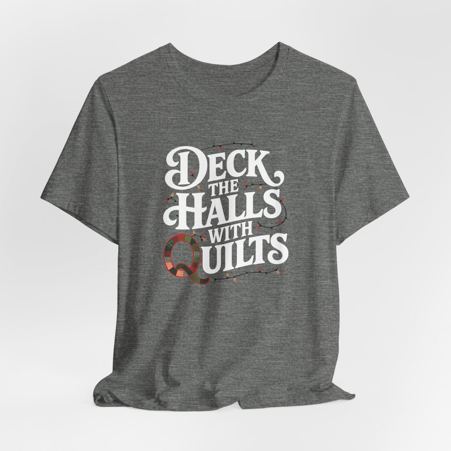 A Deep Heather christmas quilting t-shirt featuring the phrase "Deck the Halls with Quilts," adorned with holiday lights and quilting-inspired elements, including a quilted 'Q' for a humorous touch.