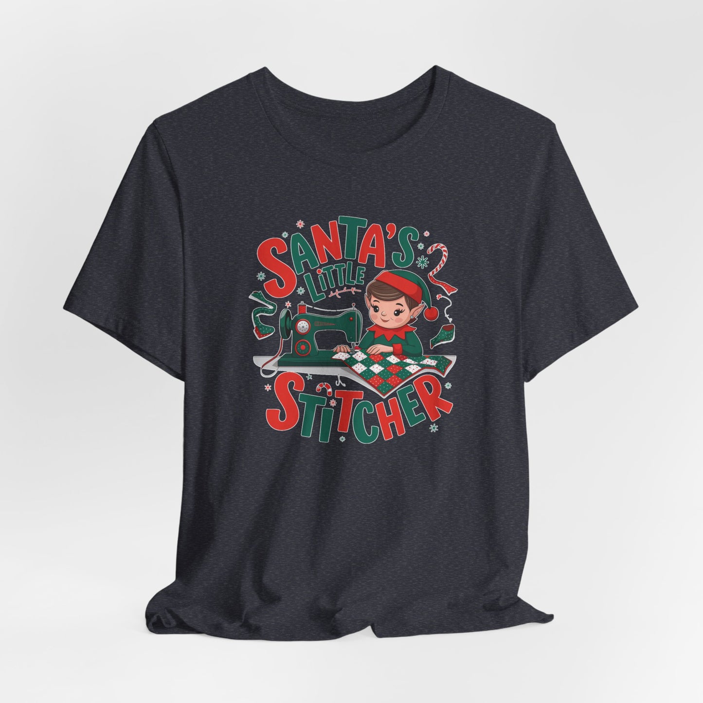 A Heather Navy christmas quilting t-shirt featuring an adorable elf is sewing a festive patchwork quilt on a sewing machine, surrounded by holiday-themed decorations, with the phrase "Santa's Little Stitcher" above and below the design.