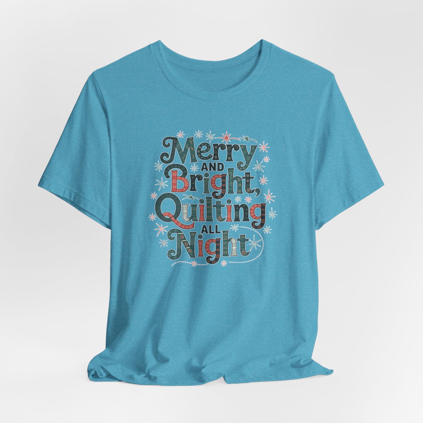 A Heather Aqua christmas quilting T-shirt featuring a whimsical design with the phrase "Merry and Bright, Quilting All Night," featuring festive quilting patterns and holiday-themed elements like stars and stitching lines. Perfect gift for quilters.