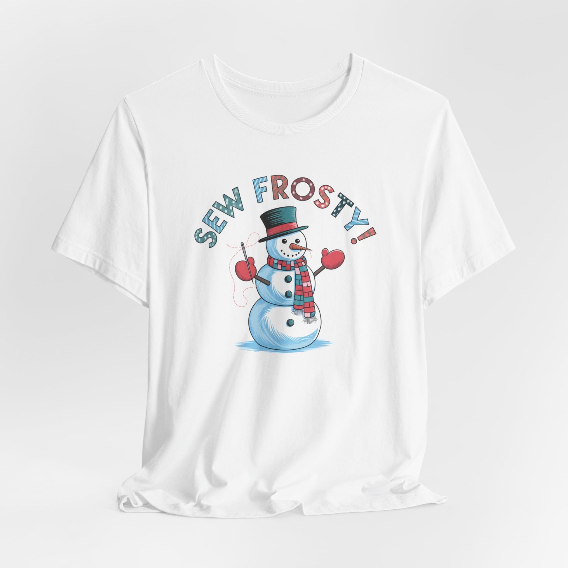 A White christmas quilting t-shirt featuring cheerful snowman design holding a sewing needle, with the phrase "Sew Frosty" in playful, winter-themed lettering. The snowman is wearing a scarf and mittens, ready for holiday sewing fun.