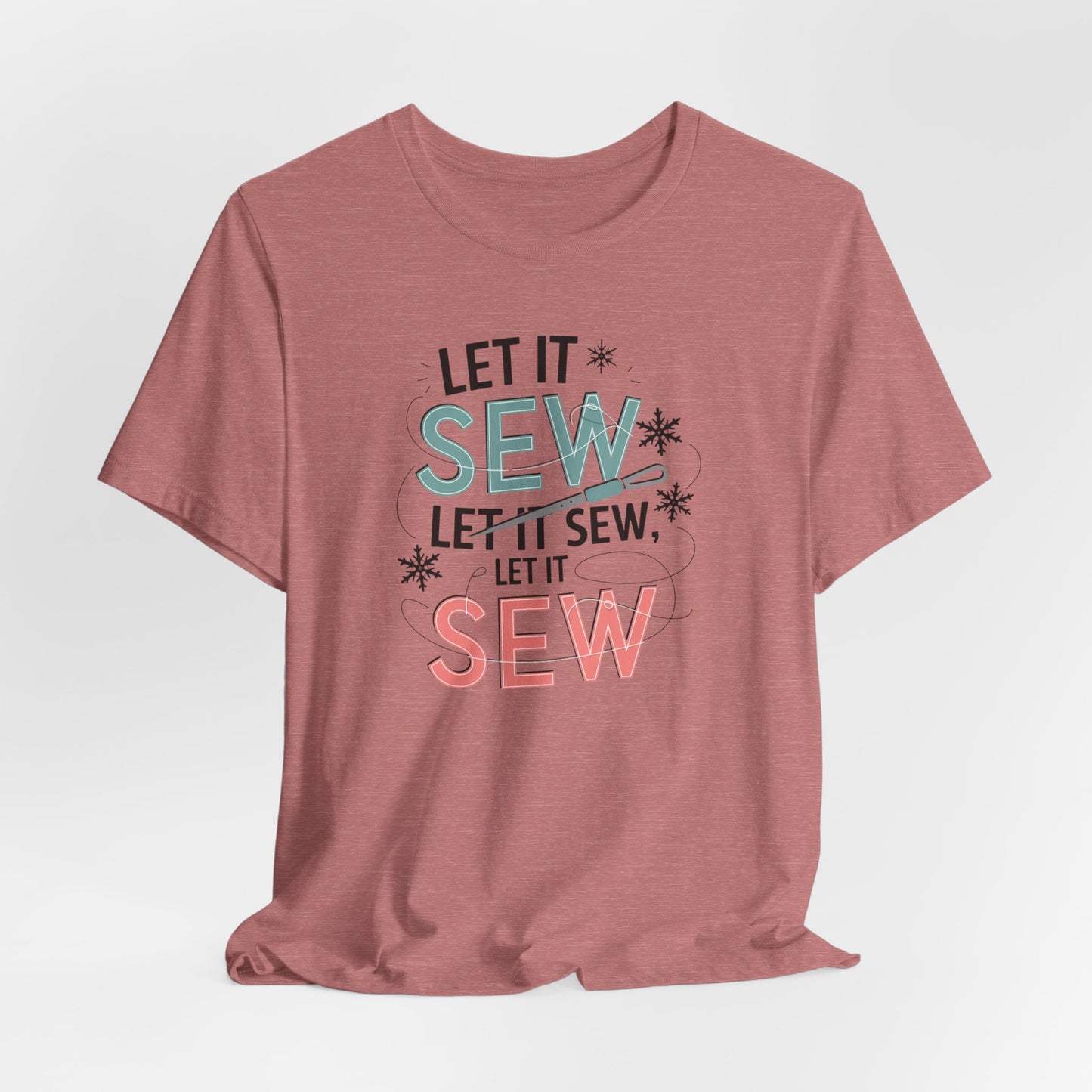 A Heather Mauve christmas quilting t-shirt featuring the phrase "Let it Sew, Let it Sew, Let it Sew" featuring a needle and thread weaving through the letters, accented by snowflakes to bring out the holiday theme.