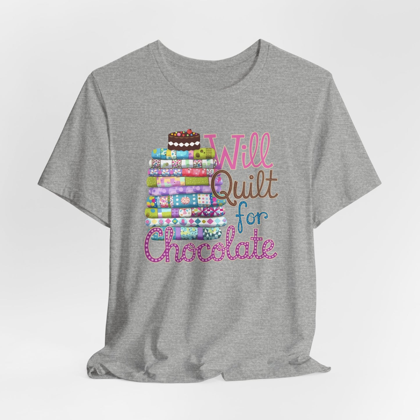 An Athletic Heather t-shirt featuring a whimsical design of a colorful stack of quilts topped with a chocolate cake and the phrase 'Will Quilt for Chocolate,' perfect for quilters who love sweets.