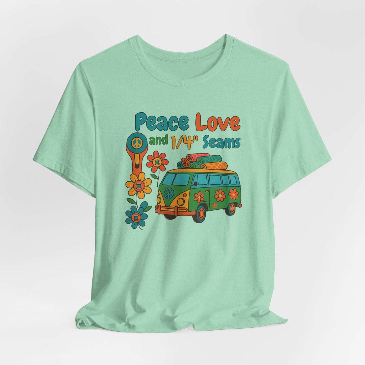 A A Heather Mint t-shirt with colorful retro design showing a peace sign rotary cutter, patchwork van, and text “Peace Love and 1/4" Seams.” Surrounded by flowers made of thread spools. Fun vintage-style quilting shirt.
