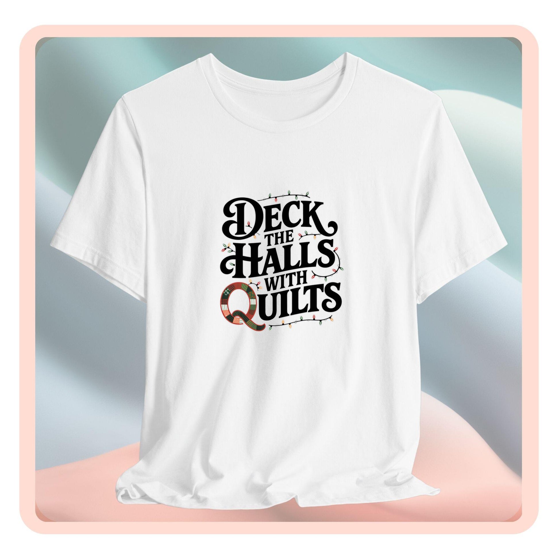 A christmas quilting t-shirt featuring the phrase "Deck the Halls with Quilts," adorned with holiday lights and quilting-inspired elements, including a quilted 'Q' for a humorous touch.
