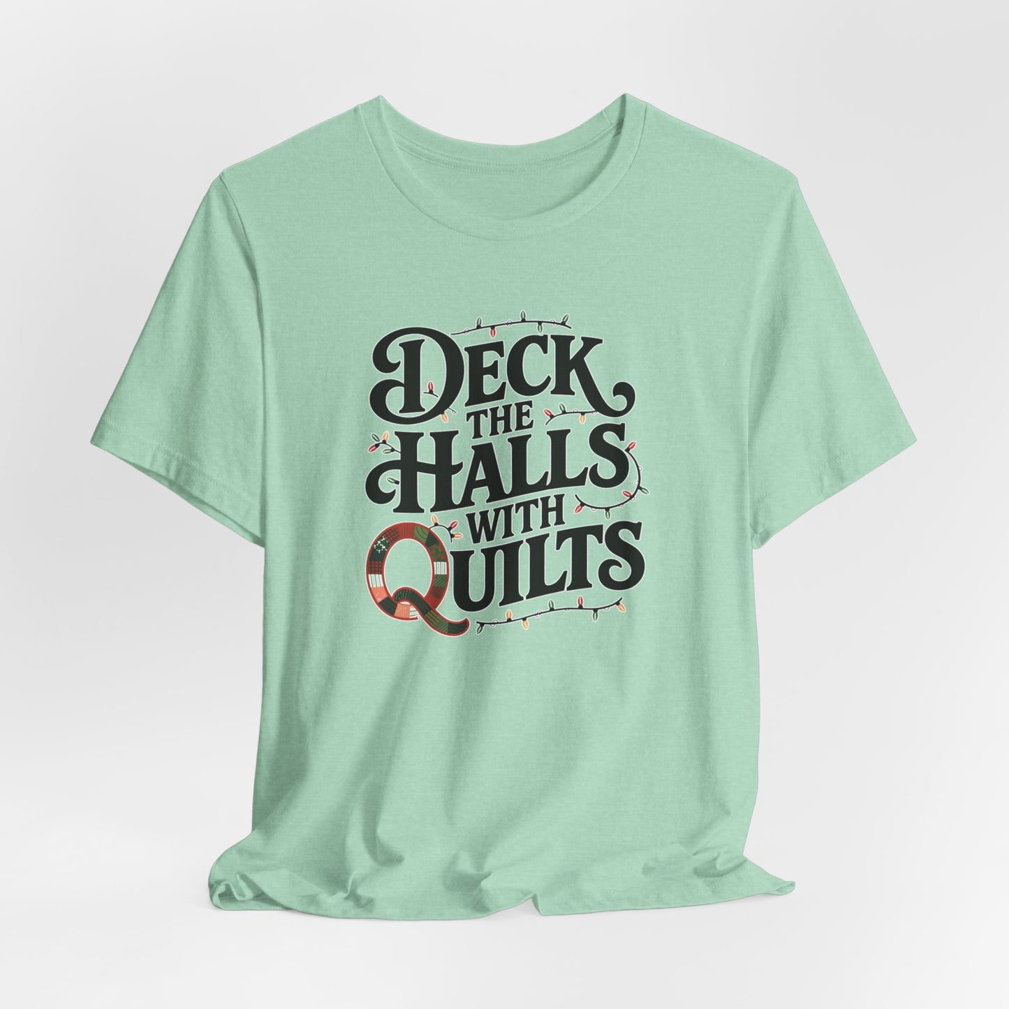 A Heather Mint christmas quilting t-shirt featuring the phrase "Deck the Halls with Quilts," adorned with holiday lights and quilting-inspired elements, including a quilted 'Q' for a humorous touch.