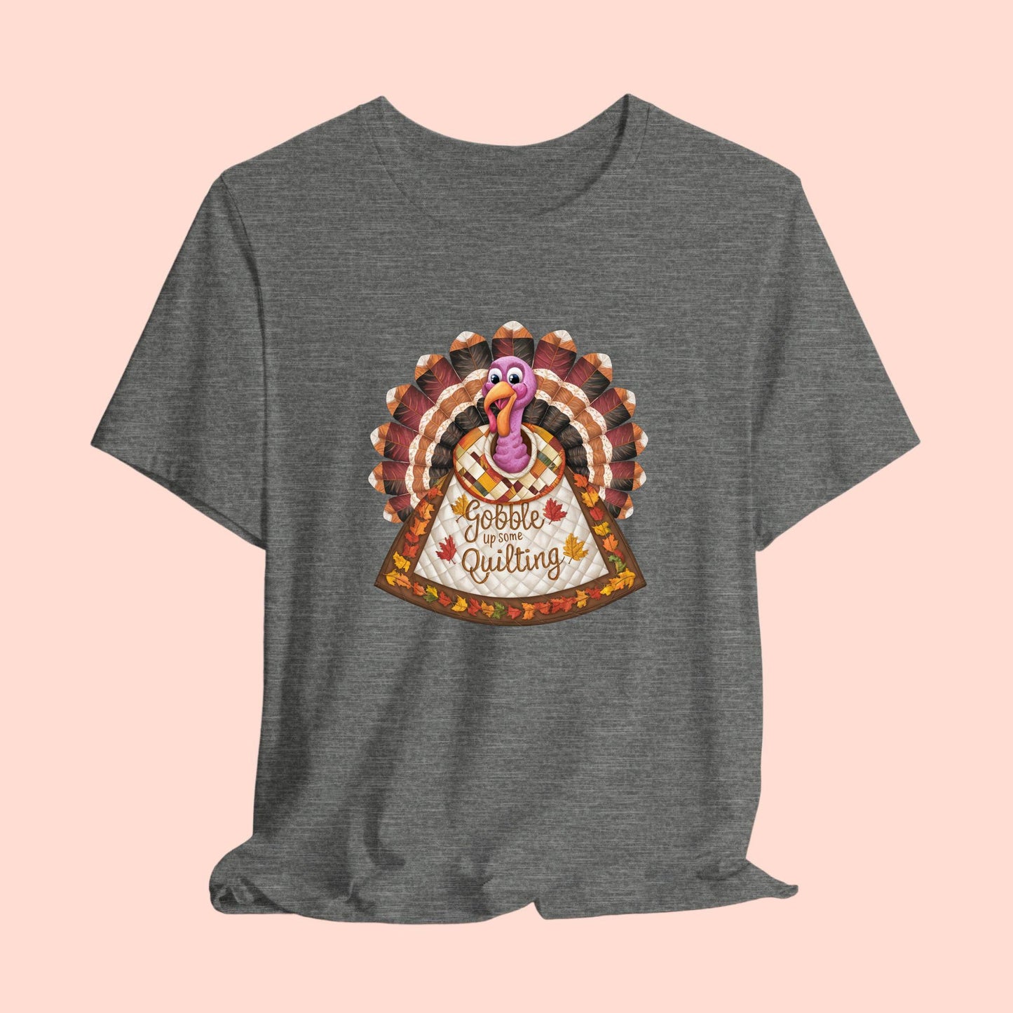 A thanksgiving quilting t-shirt featuring a quilted turkey design with colorful patchwork feathers and body. Text on turkey reads "Gobble up some Quilting" surrounded by fall leaves. Combines Thanksgiving imagery with quilting motifs in a whimsical illustration.