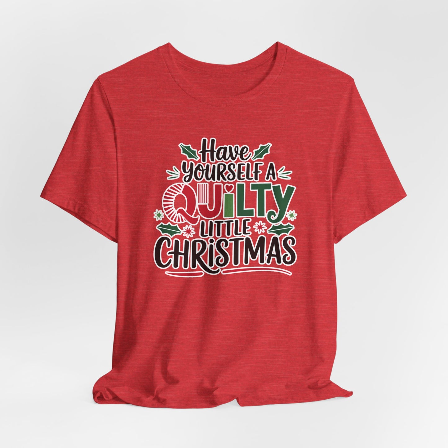 A Heather Red fun holiday-themed t-shirt featuring the phrase "Have Yourself a Quilty Little Christmas" with quilting-inspired elements and holiday decorations such as holly and stars.