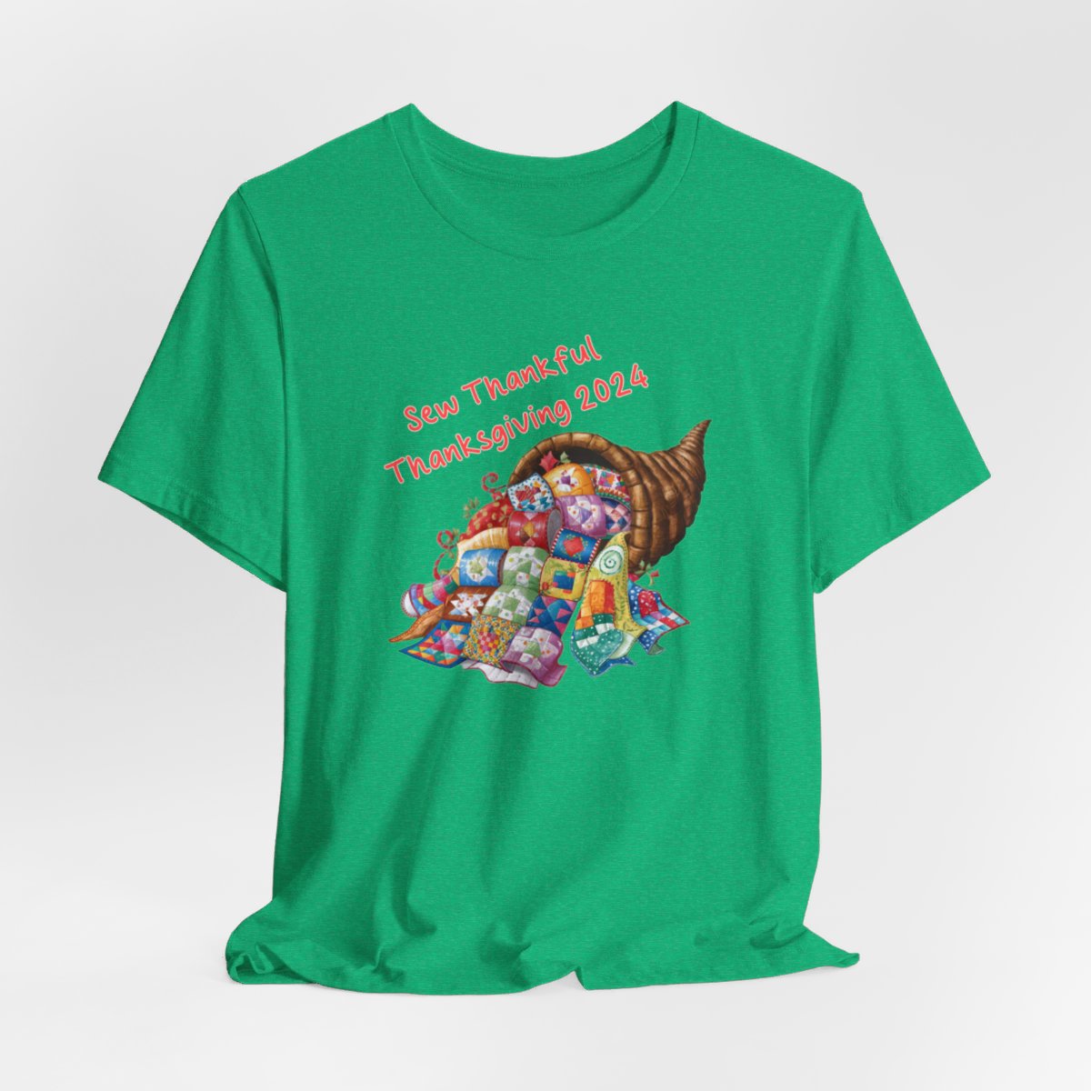 A Heather Kelly thanksgiving quilting t-shirt featuring a colorful quilted cornucopia overflowing with various quilt patterns and designs. Text reads "Sew Thankful Thanksgiving 2024" in red. Vibrant illustration combines quilting motifs with Thanksgiving imagery.