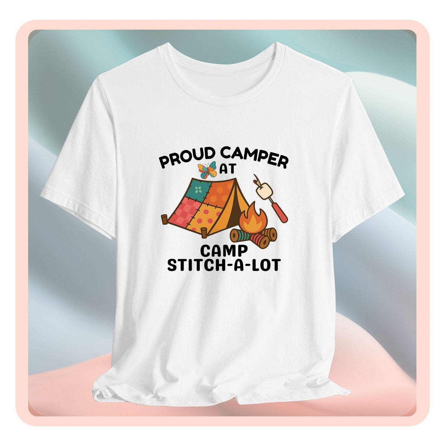 A A t-shirt featuring a colorful design with a patchwork tent, thread spool campfire, marshmallow on a seam ripper stick, and a butterfly. Text reads "Proud Camper at Camp Stitch-a-Lot." Fun gift for quilting retreats.