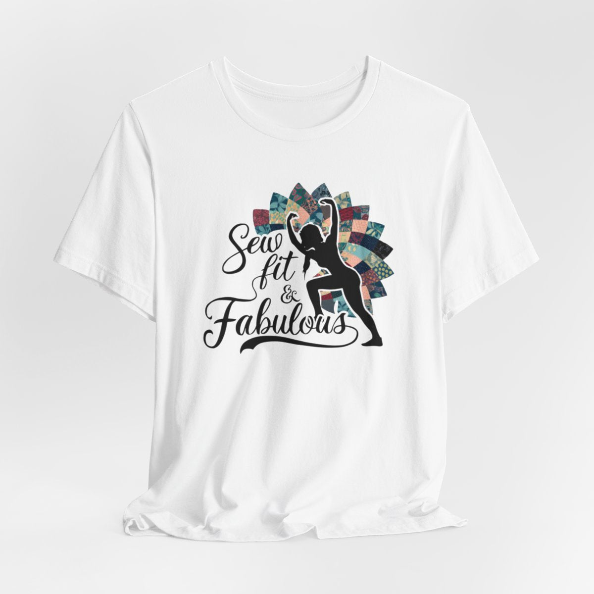 A White T-Shirt featuring a black silhouette of woman with raised arms against colorful patchwork background. Text reads "Sew fit & Fabulous" in stylized script.