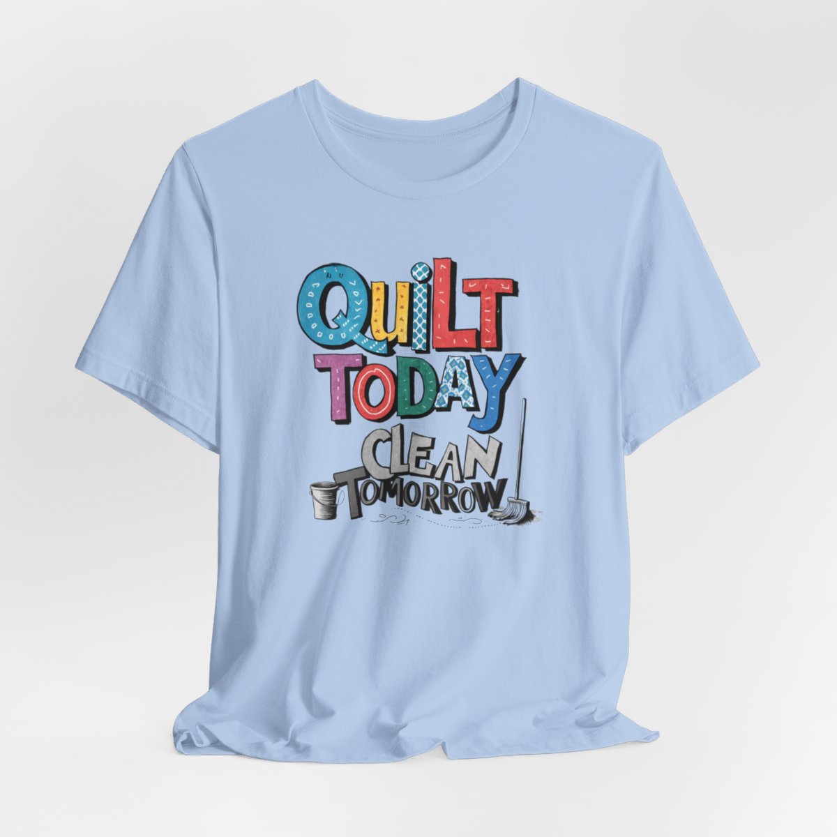 A Baby Blue funny quilting T-Shirt with the phrase Quilt Today, Clean Tomorrow in a bold and cheerful font with a broom off to the side