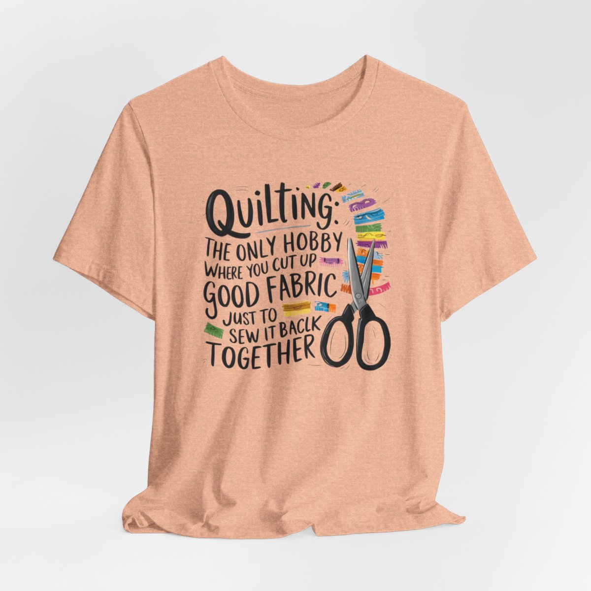 A Heather Peach Quilting-themed T-Shirt with text "Quilting: The Only Hobby Where You Cut Up Good Fabric Just to Sew it Back Together" surrounded by colorful fabric scraps and scissors.