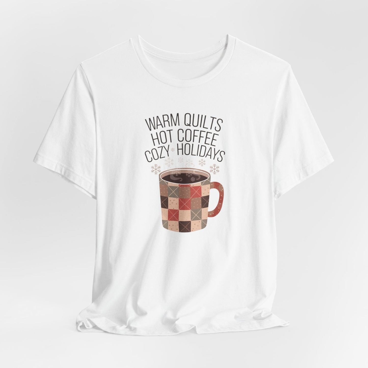 A White christmas quilting t-shirt featuring a cozy patchwork quilt-themed coffee mug, surrounded by snowflakes, with the phrase "Warm Quilts, Hot Coffee, Cozy Holidays" above the mug, celebrating the warmth of quilts and coffee during the holiday season.