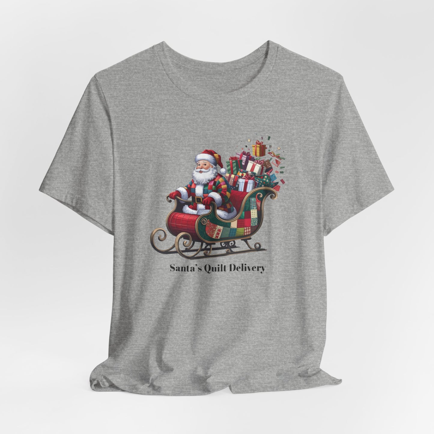 An Athletic Heather christmas quilting t-shirt featuring Santa Claus wearing a patchwork quilt coat, sitting in a sleigh filled with gifts and quilts, with the phrase "Santa's Quilt Delivery" below, combining holiday cheer and quilting fun.