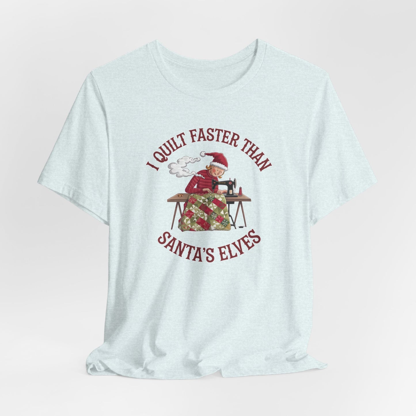 A Heather Ice Blue christmas quilting t-shirt featuring a quilter working at a sewing machine, quilting a festive holiday quilt, with the phrase "I Quilt Faster Than Santa's Elves" above the image, highlighting the speed and skill of the quilter.