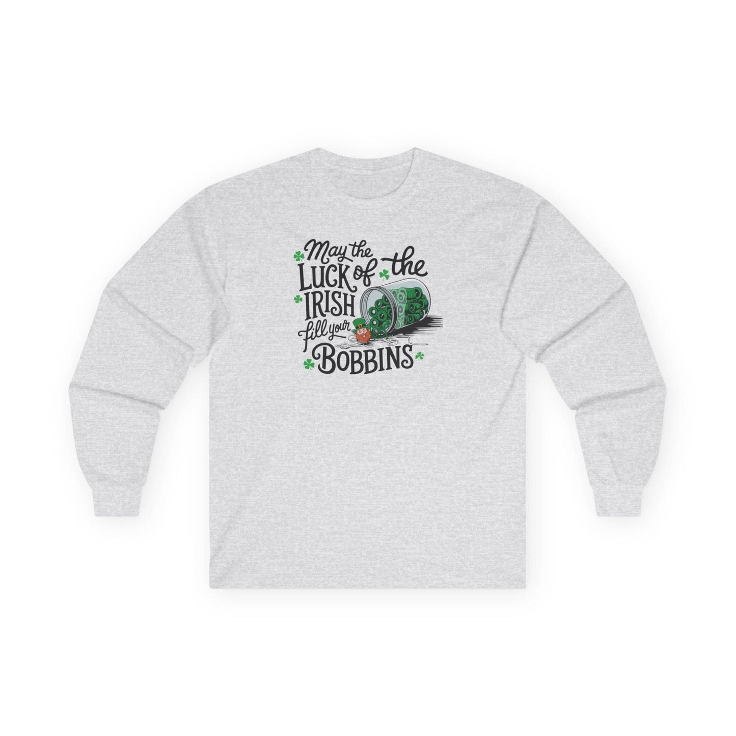 An Ash long-sleeve t-shirt featuring a festive design with shamrocks, a spool of green thread, and the phrase 'May the Luck of the Irish Fill Your Bobbins,' perfect for quilters celebrating St. Patrick’s Day.