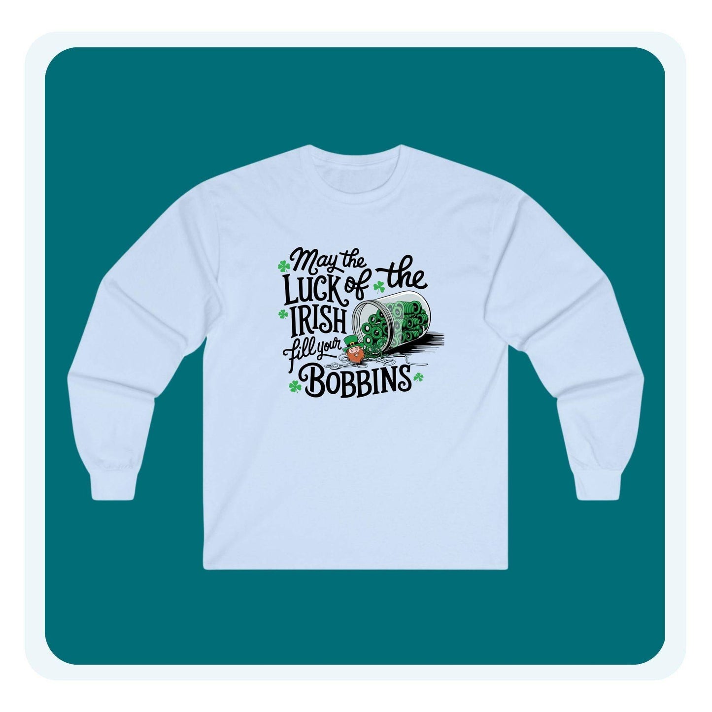 A long-sleeve t-shirt featuring a festive design with shamrocks, a spool of green thread, and the phrase 'May the Luck of the Irish Fill Your Bobbins,' perfect for quilters celebrating St. Patrick’s Day.