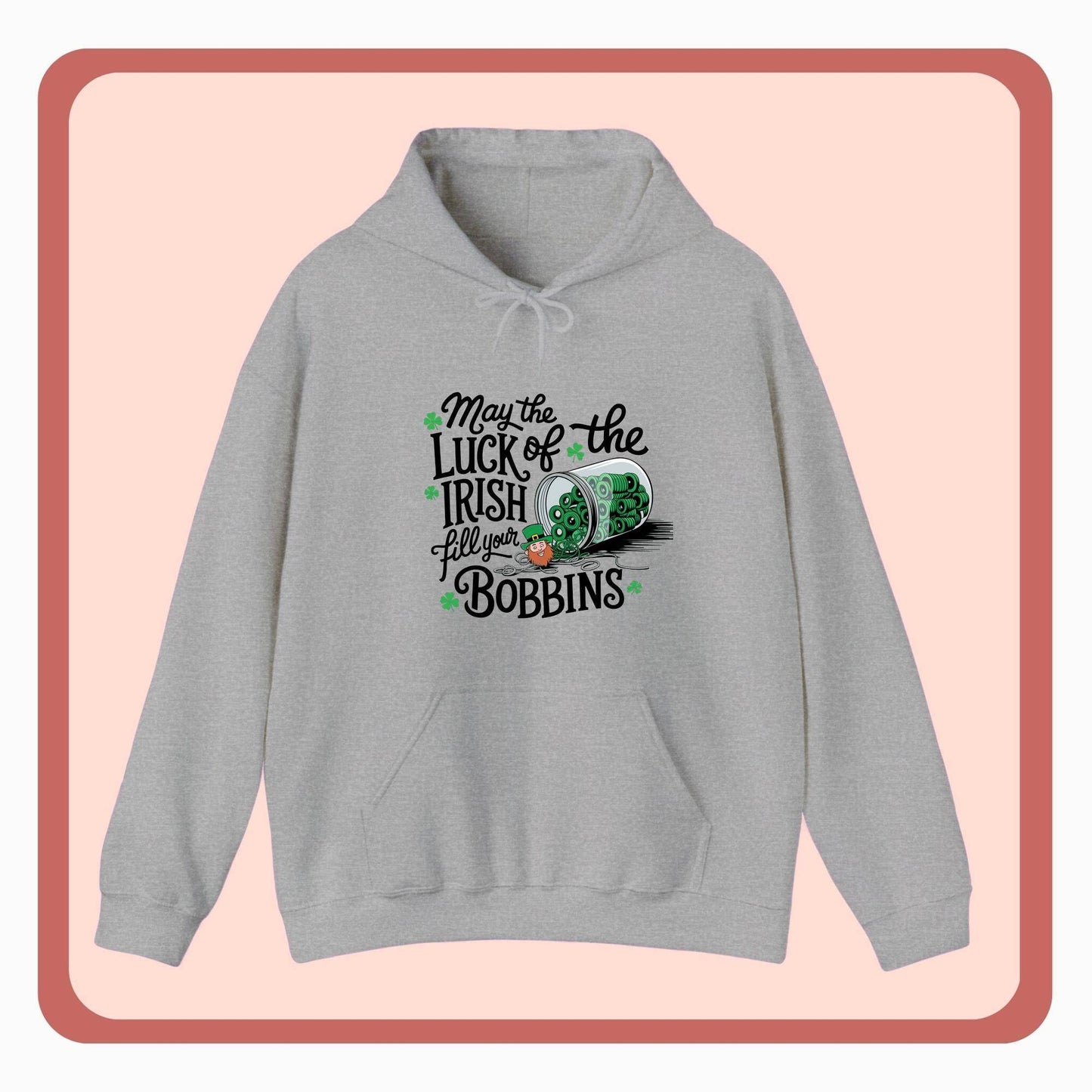 A hoodie featuring a festive design with shamrocks, a spool of green thread, and the phrase 'May the Luck of the Irish Fill Your Bobbins,' perfect for quilters celebrating St. Patrick’s Day.