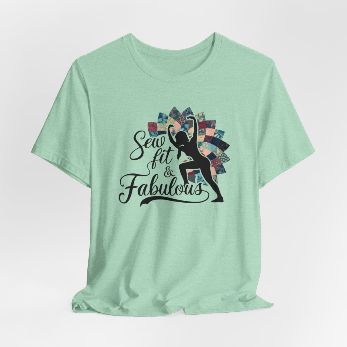 A Heather Mint T-Shirt featuring a black silhouette of woman with raised arms against colorful patchwork background. Text reads "Sew fit & Fabulous" in stylized script.