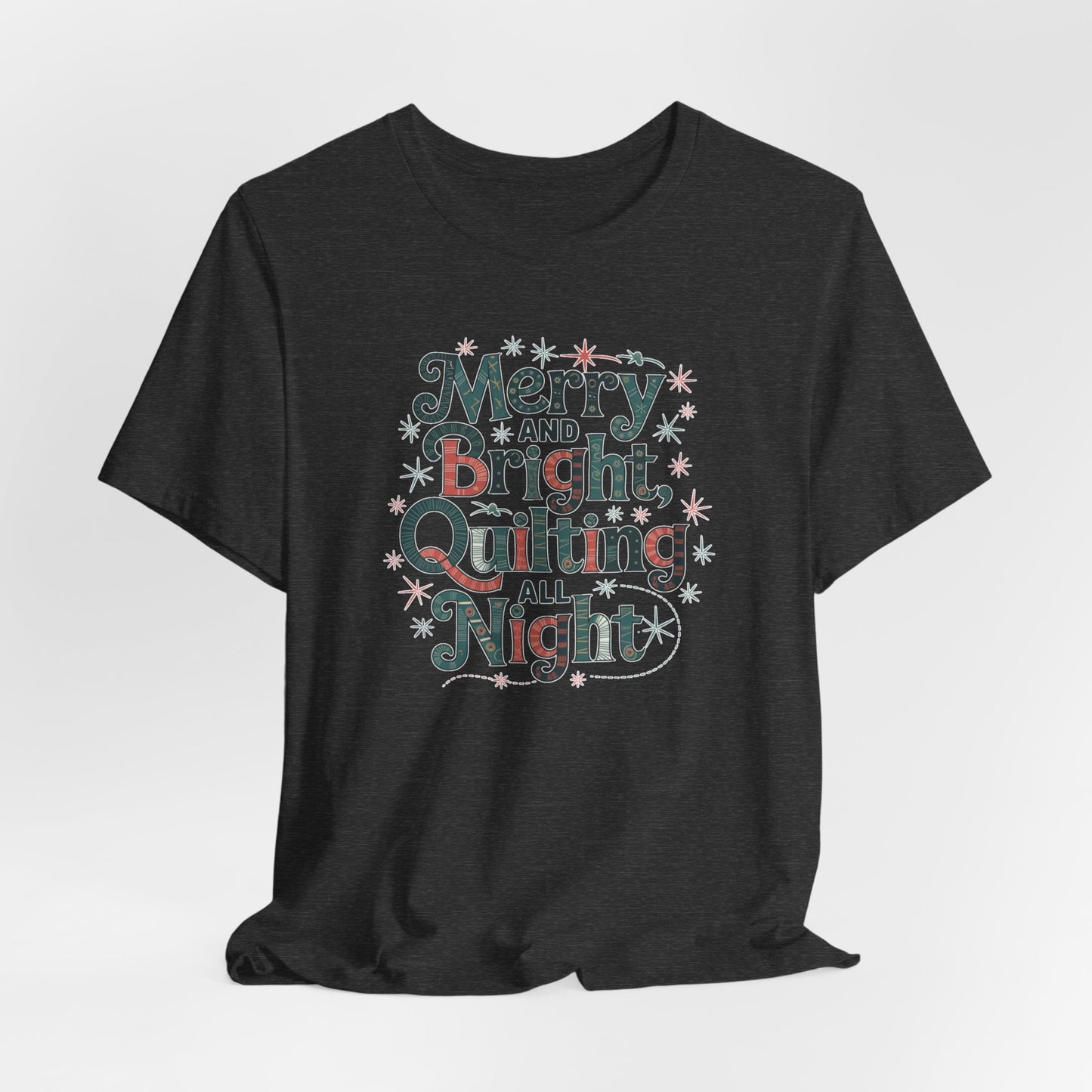 A Dark Grey Heather christmas quilting T-shirt featuring a whimsical design with the phrase "Merry and Bright, Quilting All Night," featuring festive quilting patterns and holiday-themed elements like stars and stitching lines. Perfect gift for quilters.