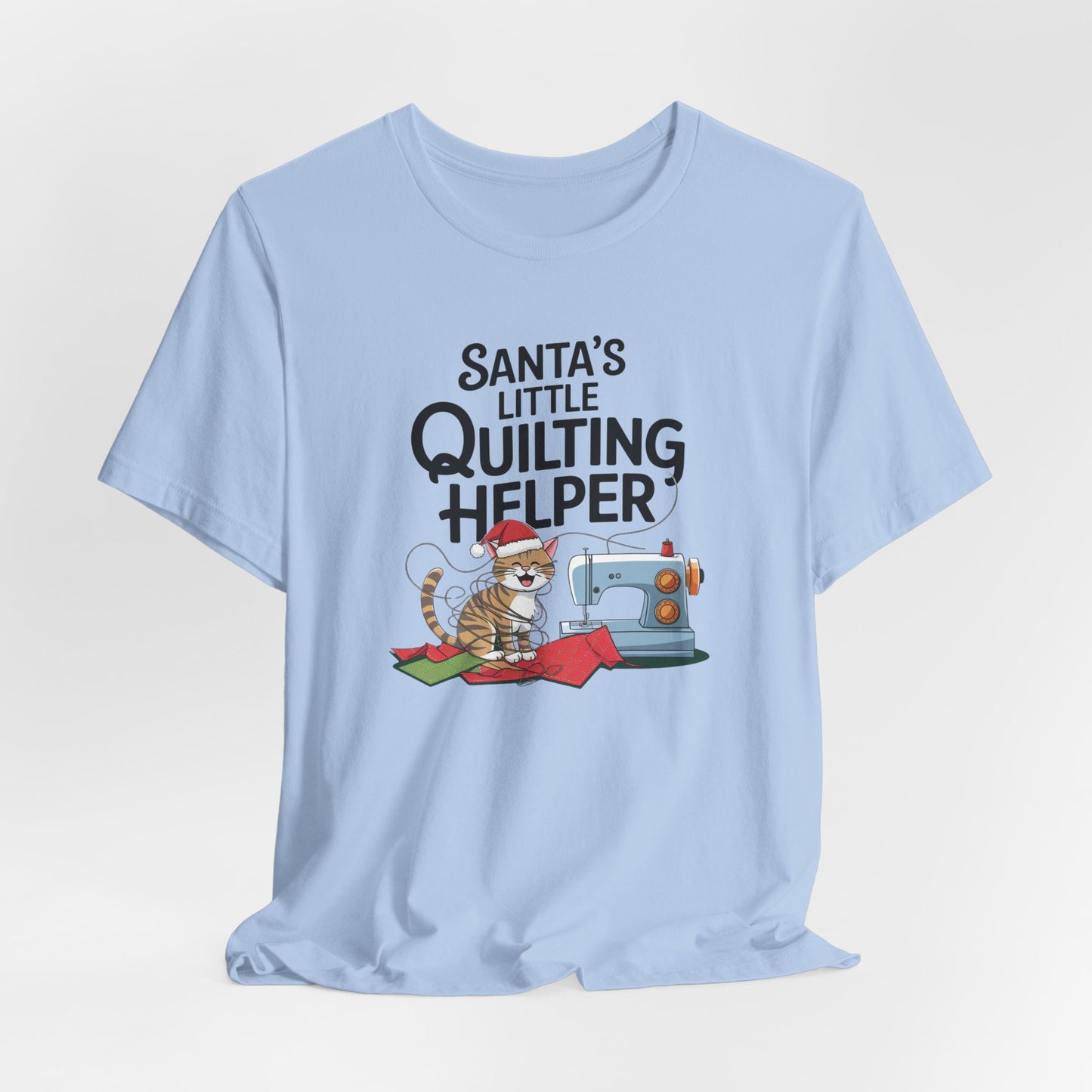 A Baby Blue christmas quilting t-shirt featuring a playful cat wearing a Santa hat is tangled in thread next to a sewing machine, with the phrase "Santa's Little Quilting Helper" above, combining quilting and holiday humor.
